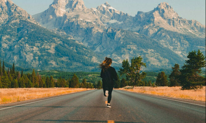 woman running on mountain with beautiful mountain in front of her