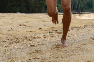 Barefoot runner on beach