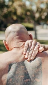 Man rubbing pain in upper back