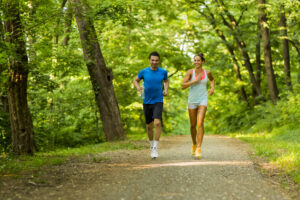 man and woman running in a forest path